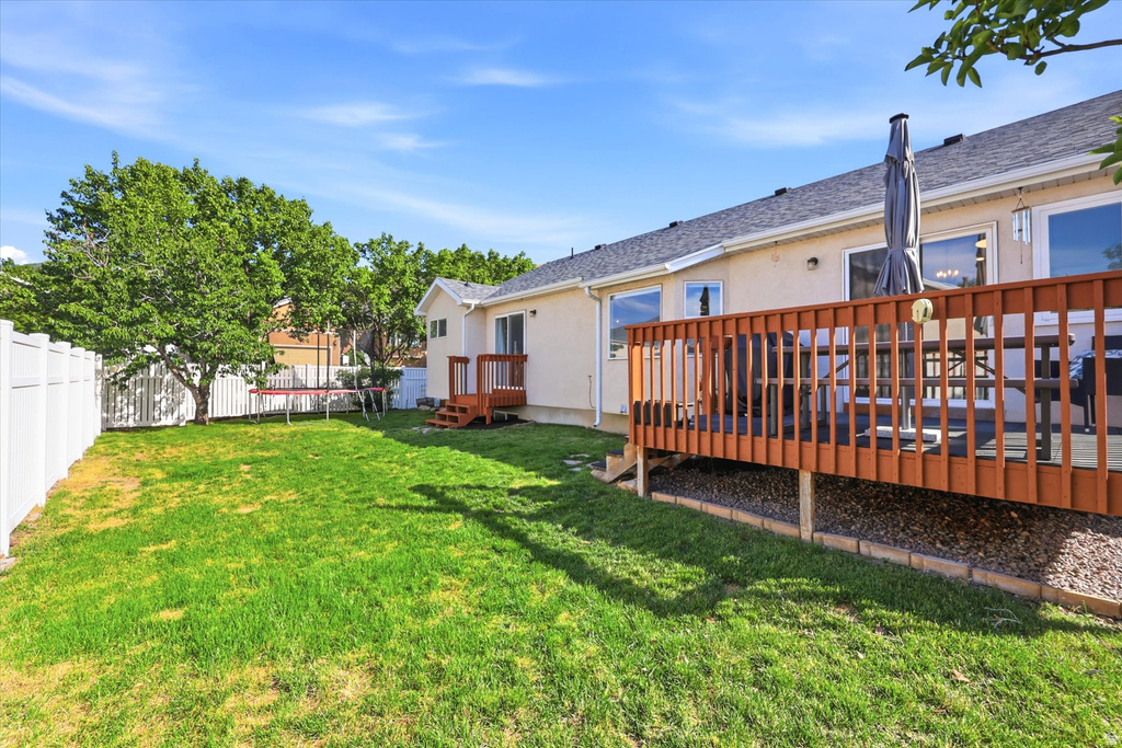 Expansive backyard featuring a manicured lawn, a full-height privacy fence, and mature trees