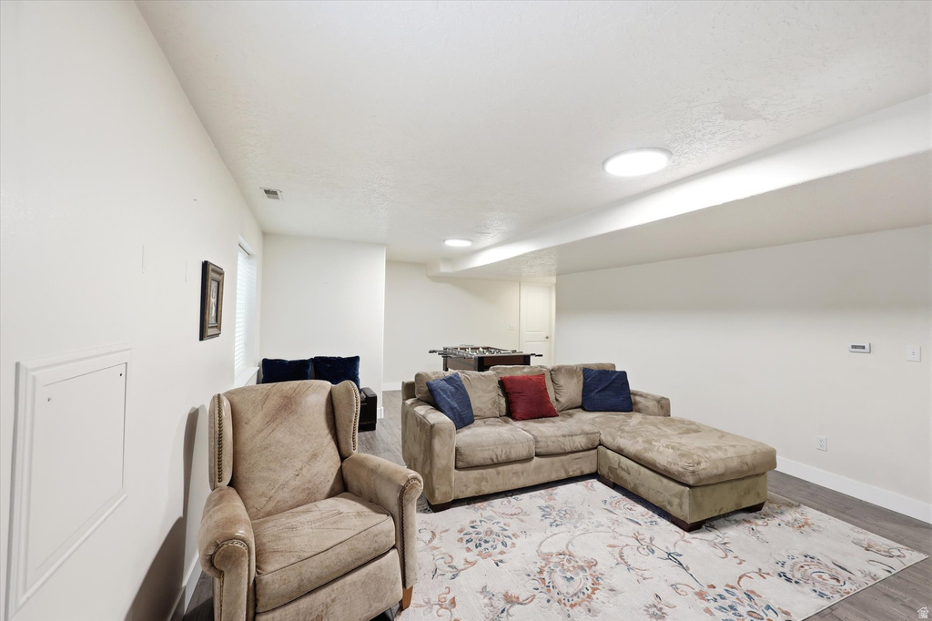 Spacious lower-level area featuring recessed lighting, a window with blinds, and wood-finish flooring