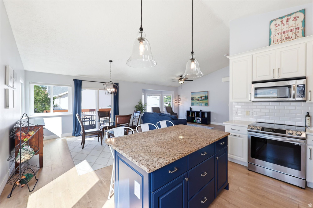 Kitchen island with a granite countertop, navy base cabinetry, and pendant lighting