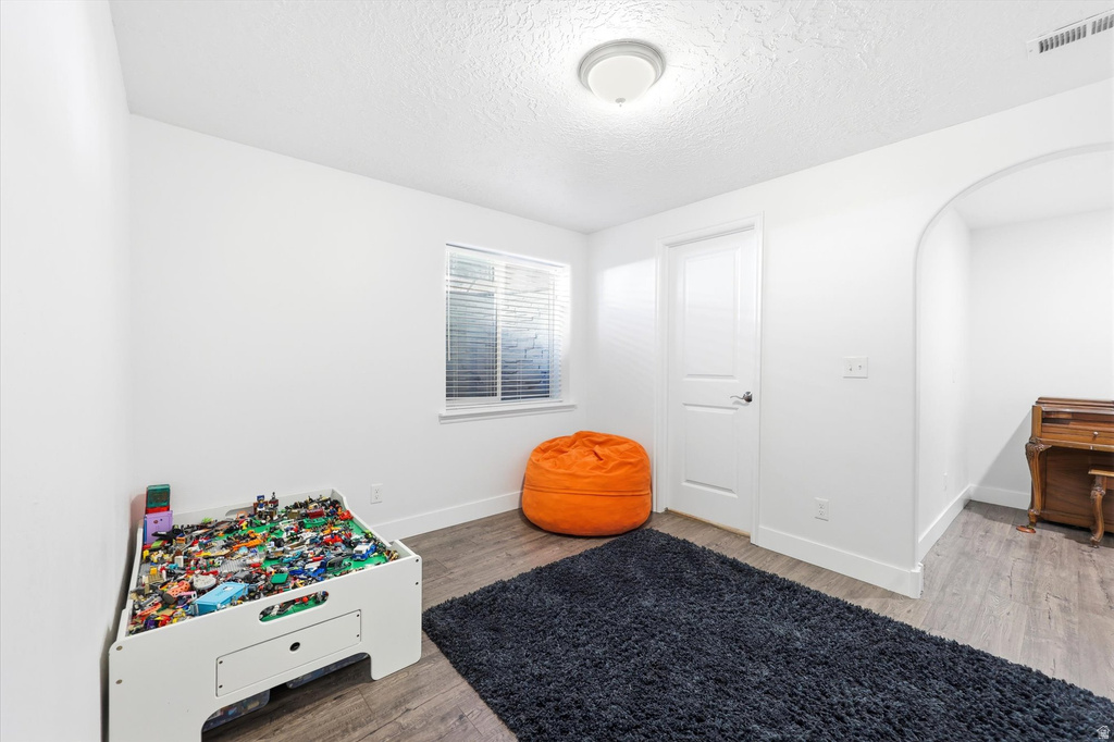 Room featuring wood-finish flooring, a white interior door, and a window with horizontal blinds