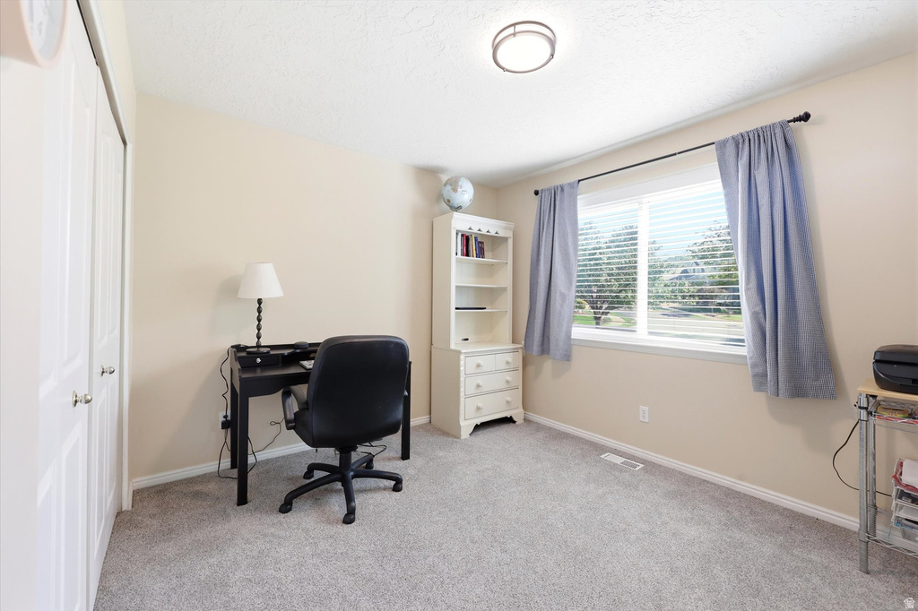 Bright room featuring a large window, neutral wall paint, and light-colored carpet