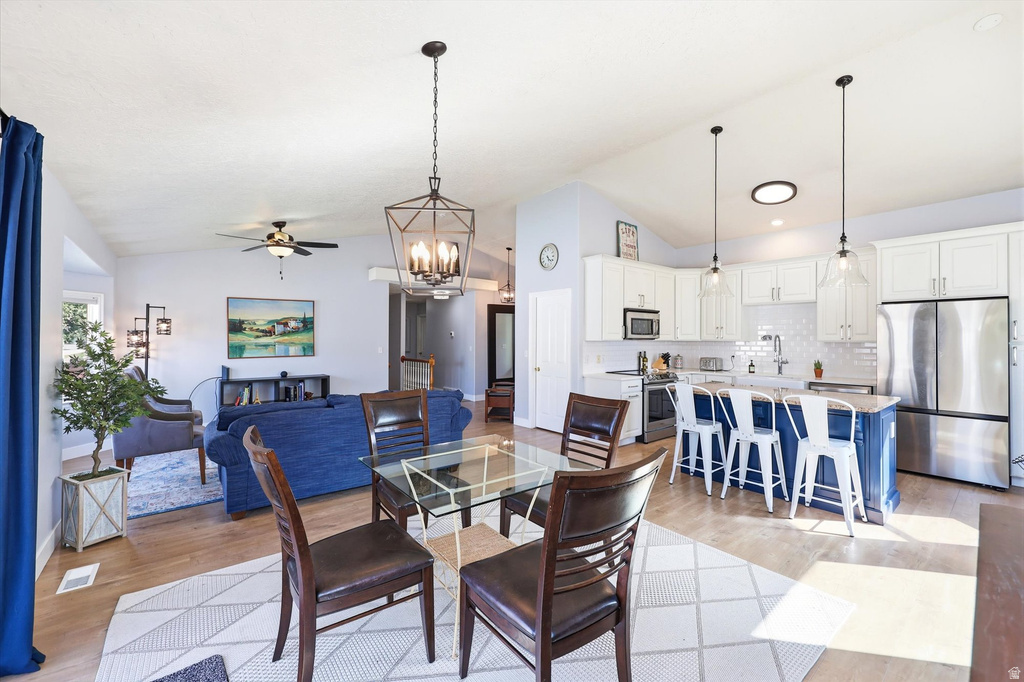 Open-concept living space featuring wood-finish flooring, a vaulted ceiling, and recessed lighting