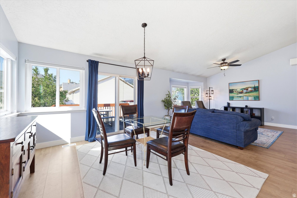 Open-concept living space featuring wood-finish flooring, vaulted ceilings, and a bay window