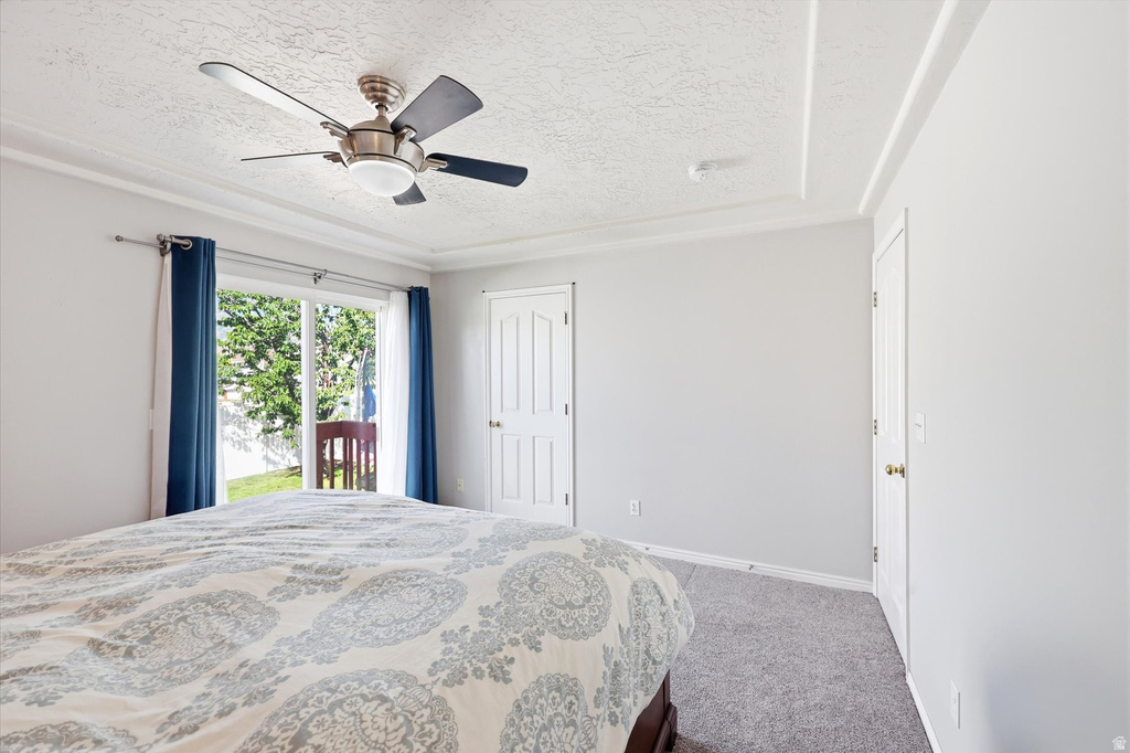 Sliding glass door opening to outdoor space, ceiling fan, tray ceiling with crown molding, and two panel doors