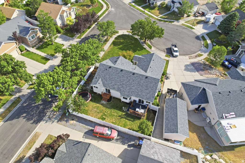 Aerial perspective showcasing a residential property with a shingled roof and a fenced backyard