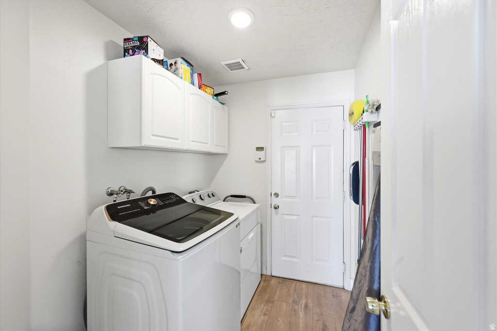 Dedicated laundry space featuring wood-finish flooring, white built-in cabinetry, and a panel door