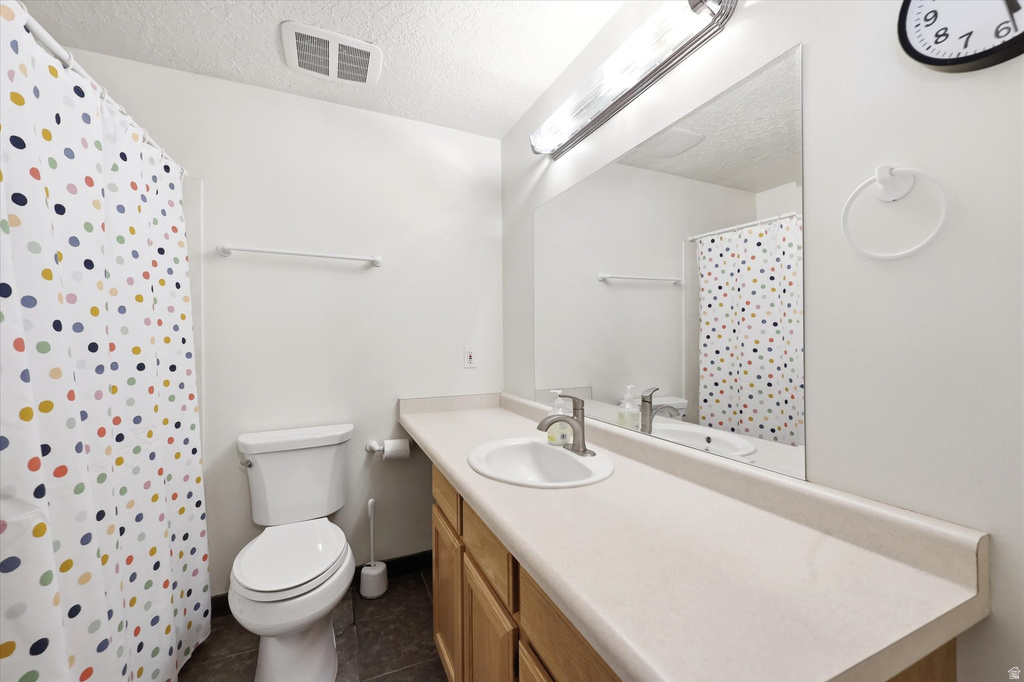 Bathroom featuring an integrated vanity sink, expansive wall-mounted mirror, light wood-finish cabinetry, and a white toilet