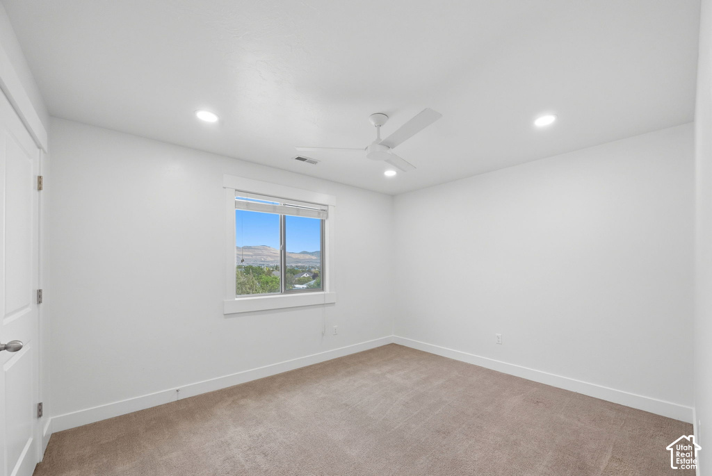 Bright room featuring a window with mountain and greenery scenery, light brown carpet flooring, a ceiling fan, and recessed lighting