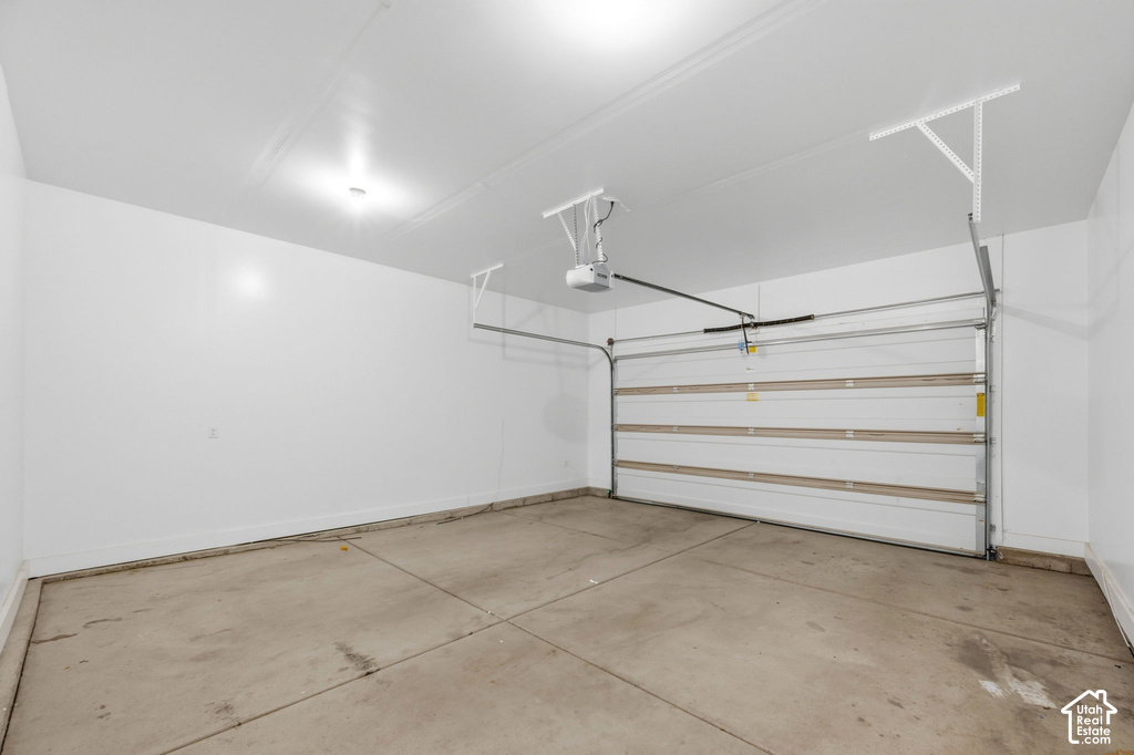 Spacious garage featuring a concrete floor, white walls, and an overhead garage door opener mechanism