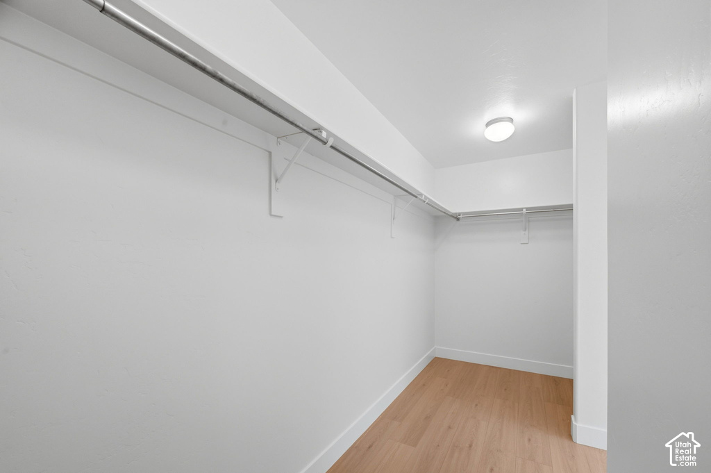 Walk-in closet featuring light wood-finish flooring, white walls, and a recessed ceiling light