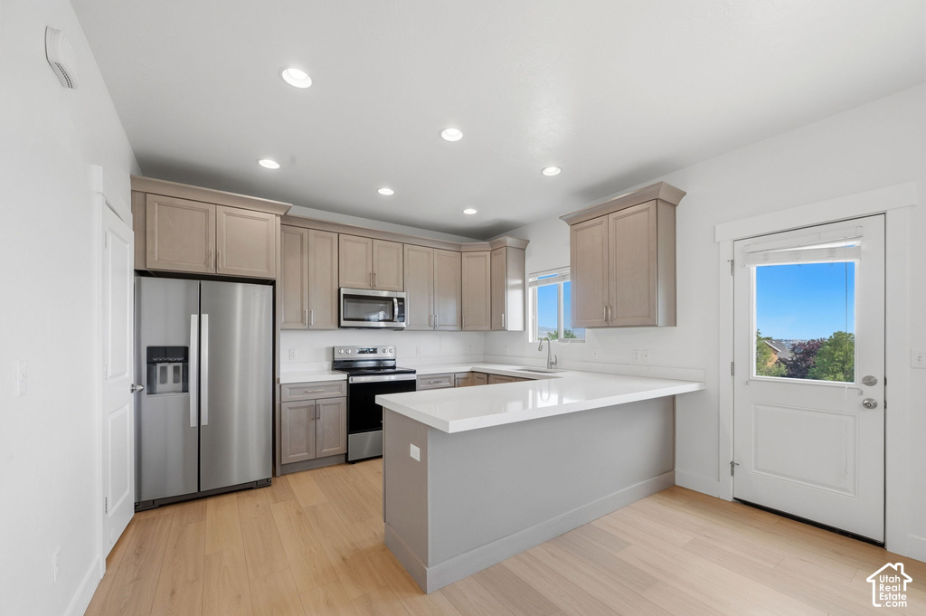 Modern kitchen featuring light wood-finish flooring, recessed lighting, and a white backsplash