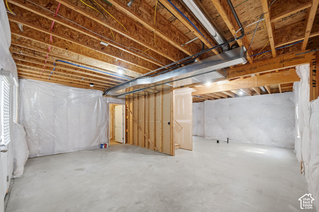 Unfinished basement featuring exposed wood joists, concrete flooring, and pre-framed interior walls