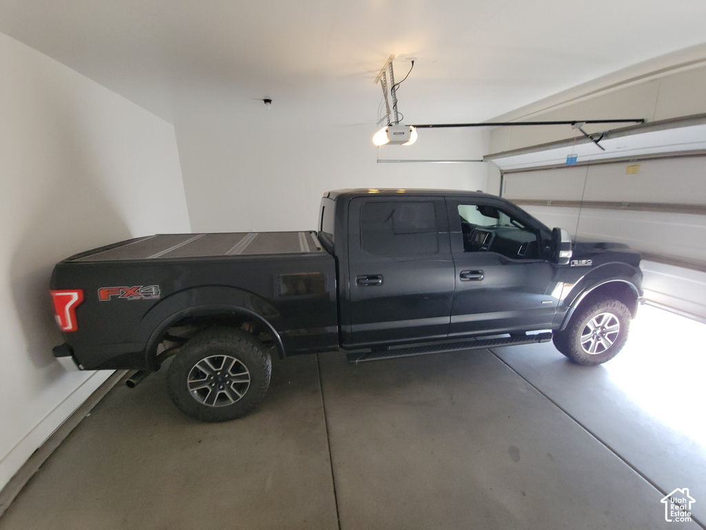 Attached garage featuring concrete flooring, an automatic garage door opener, and a panel-style garage door