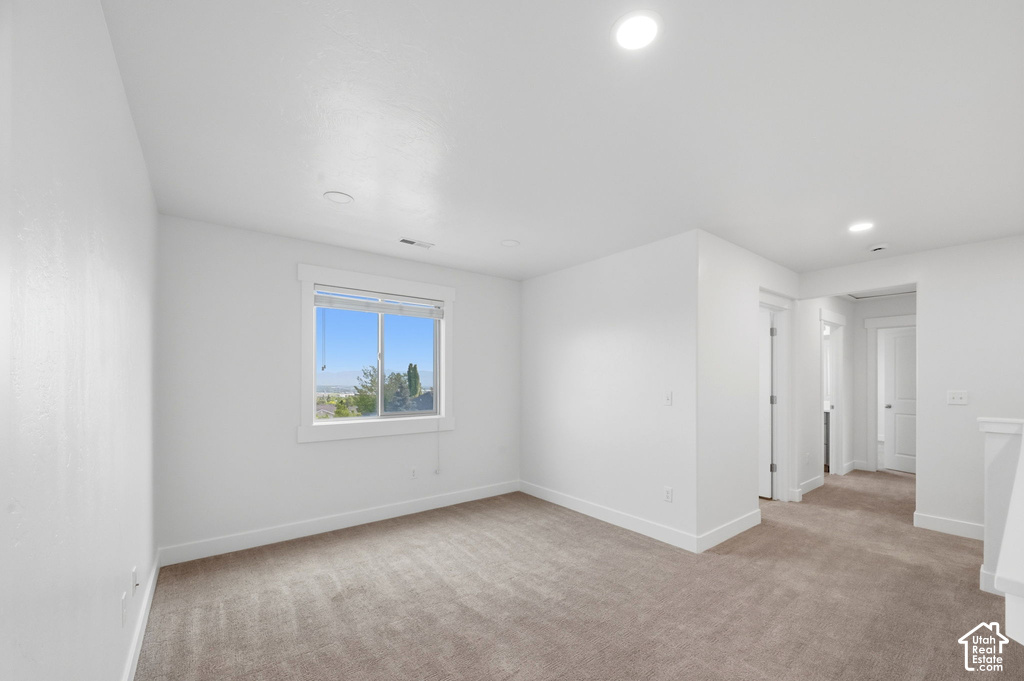 Bright room featuring a window with a distant landscape, neutral carpeting, white baseboards, and recessed lighting