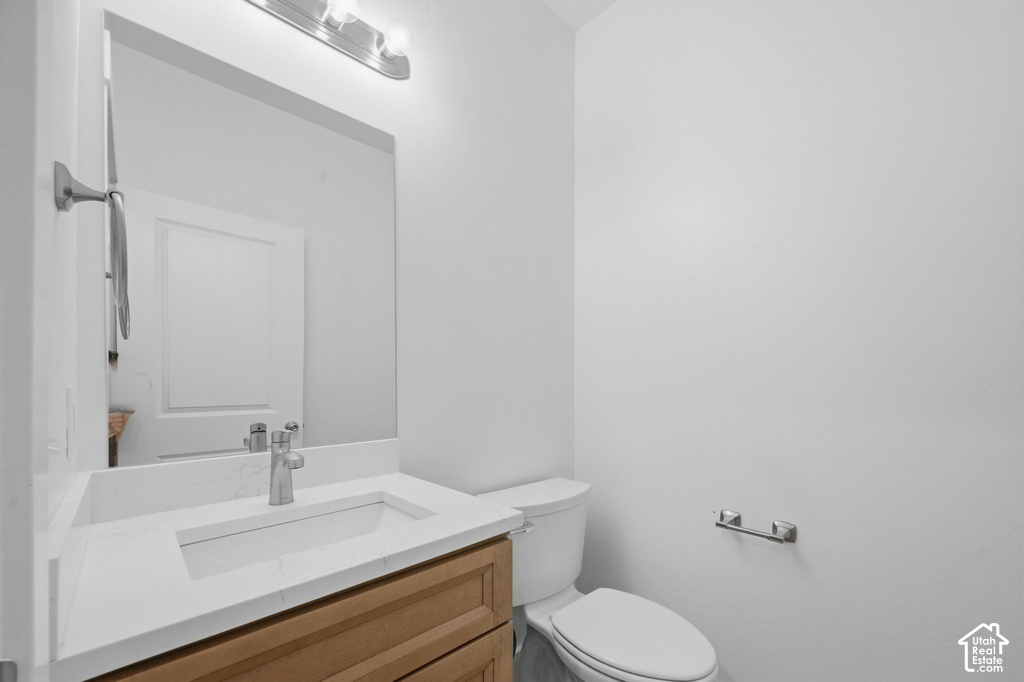 Modern bathroom vanity featuring wood-finish cabinetry, a white countertop with an integrated rectangular sink, and a chrome faucet