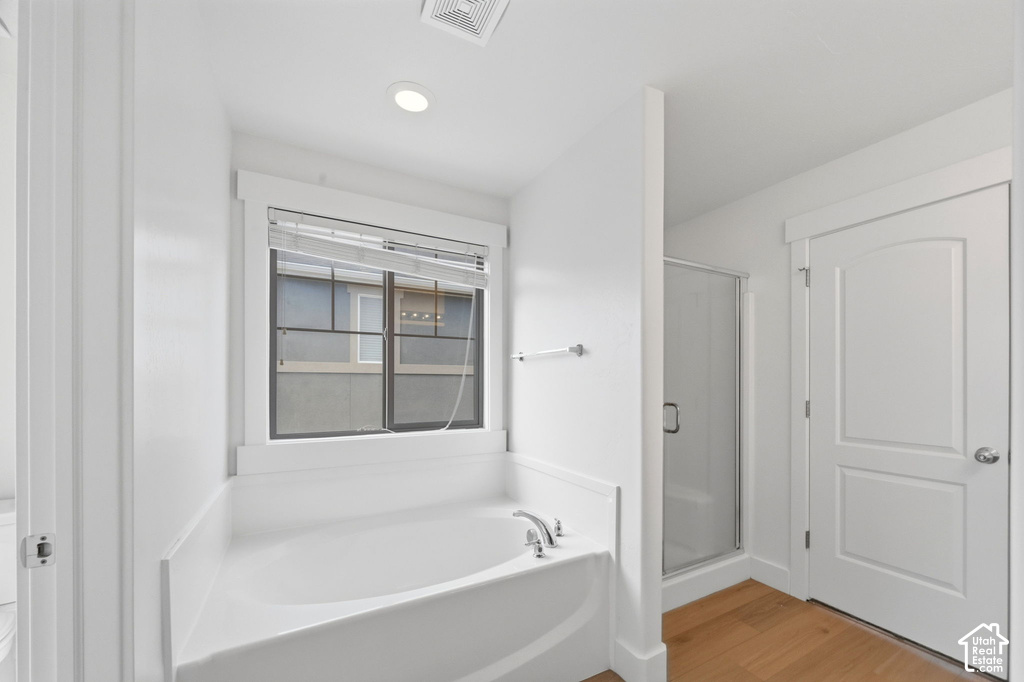 Soaking tub with chrome fixtures, framed window, and white blinds