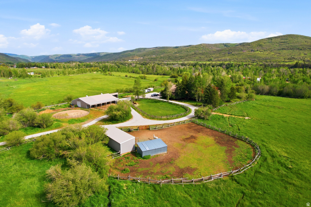 Expansive property featuring multiple outbuildings, fenced enclosures, vast green pastures, a large barn, and a gravel driveway system