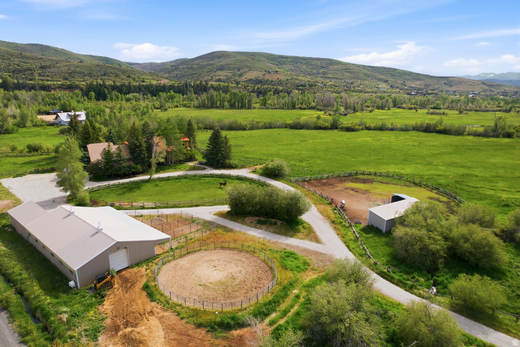 Expansive property featuring a large metal-sided outbuilding with a light-colored roof, multiple fenced enclosures, and a circular riding arena