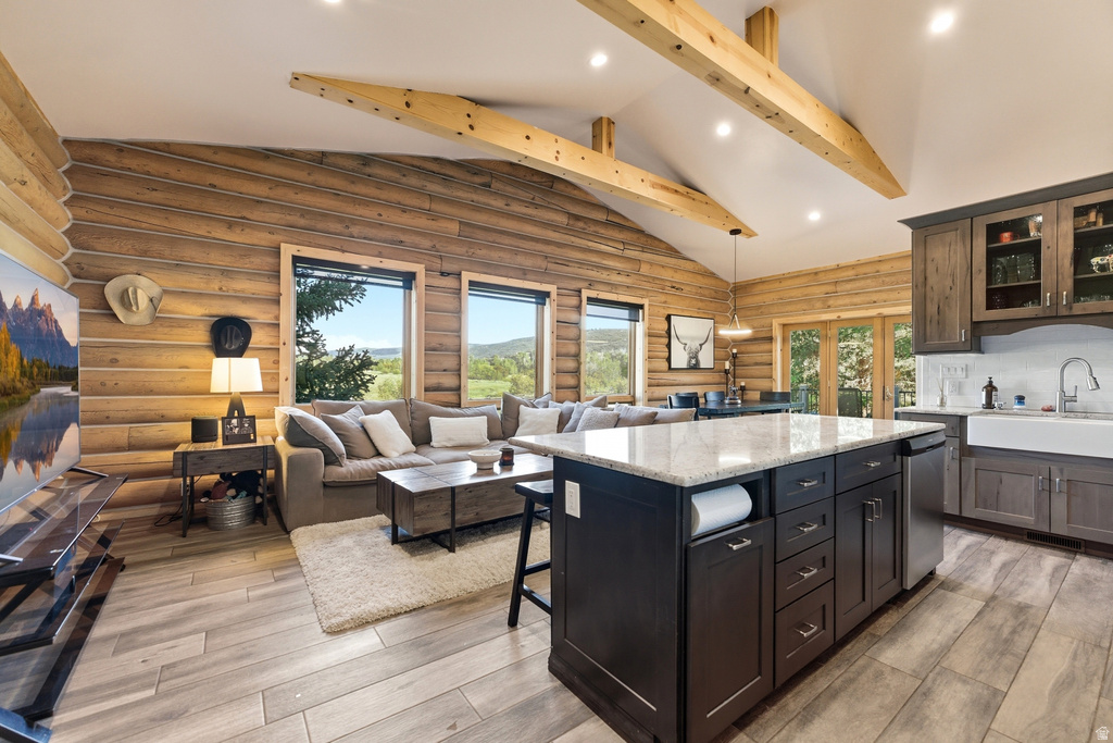 Open-concept living space featuring wood-finish flooring, exposed ceiling beams, and vaulted ceilings
