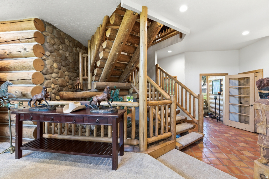 Rustic log staircase featuring log railings and carpeted treads