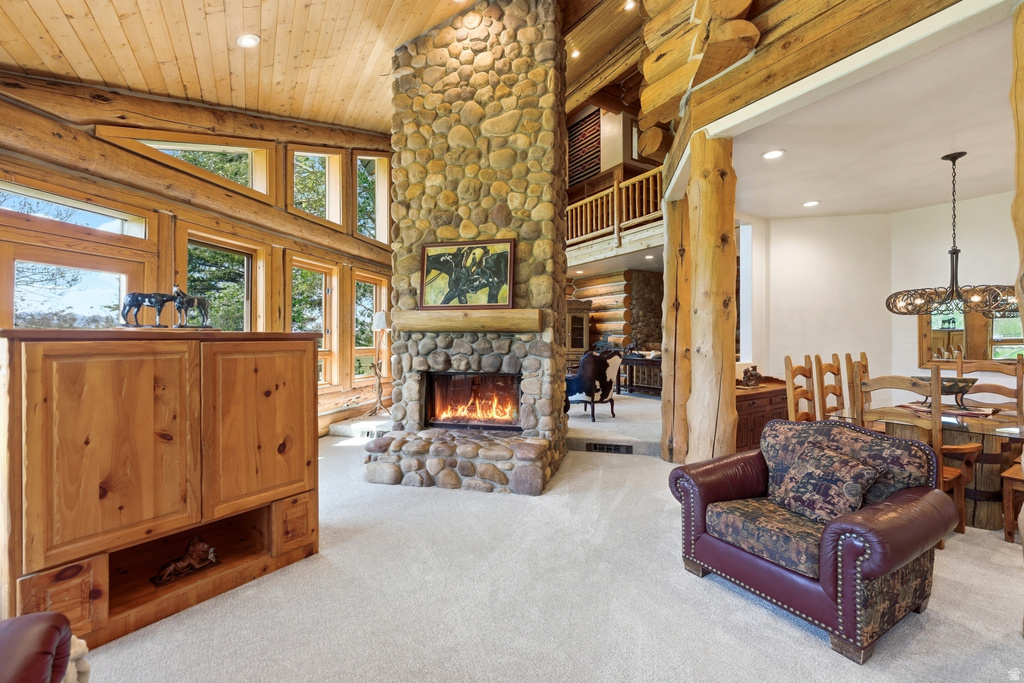 Great room featuring a floor-to-ceiling stone fireplace, high wood-paneled ceilings, and log beam construction