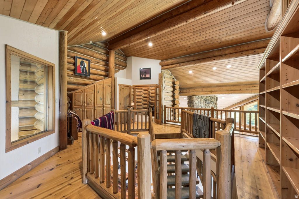 Open-concept loft area featuring wood-finish flooring, exposed wood beams, and built-in shelving