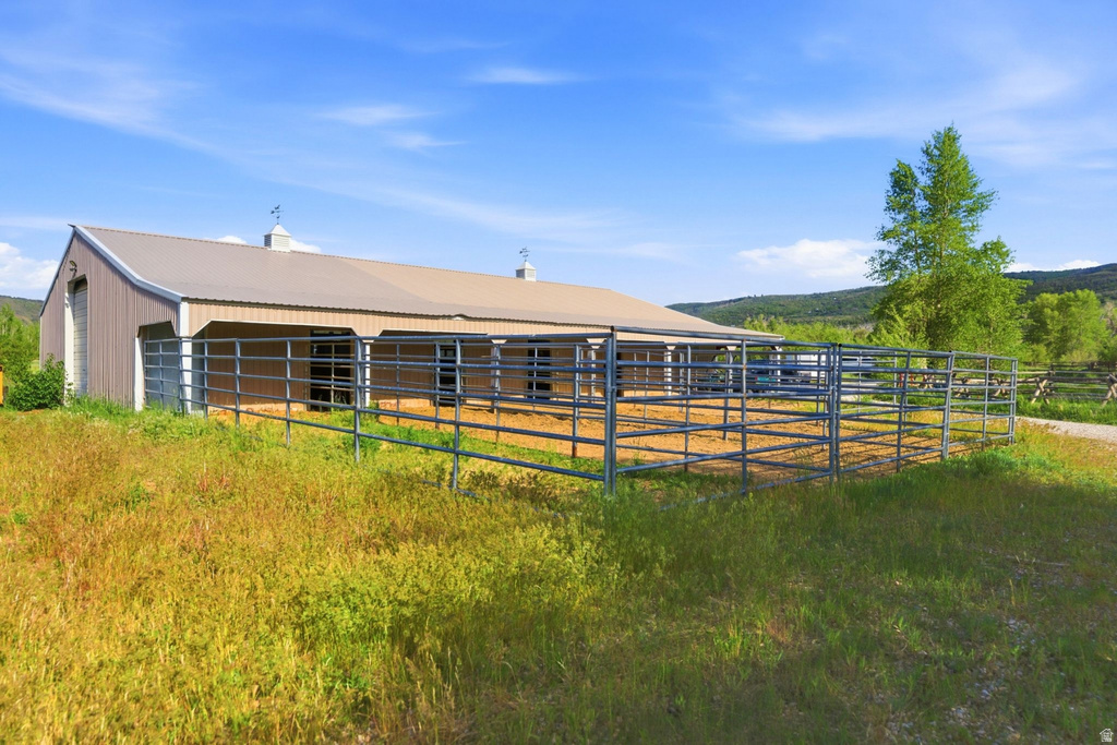 Expansive equestrian facility featuring a large barn with multiple stalls, metal panel siding, a durable metal roof, and integrated turnout pens