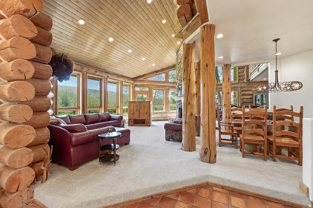 Expansive living area featuring exposed log construction, vaulted wood-finish ceiling, and large windows providing abundant natural light