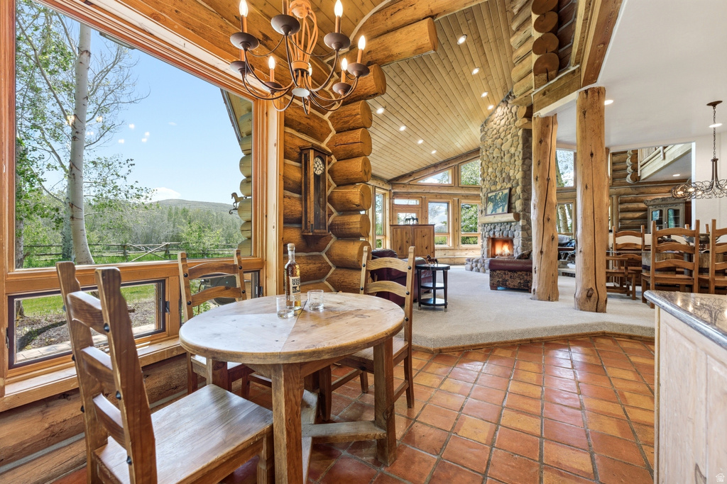 Open-concept living space featuring wood-finish flooring, exposed log beams, a stone fireplace, wood-framed windows, and a vaulted wood-paneled ceiling