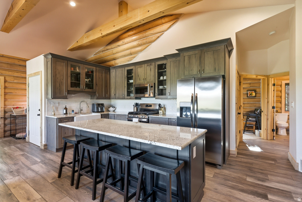 Kitchen featuring wood-finish flooring, exposed wood beams, and log wall accents