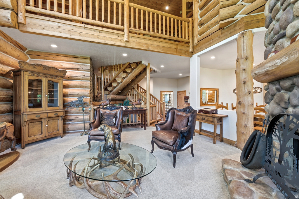 Expansive interior featuring log construction, a stone fireplace, and a log staircase leading to an upper-level balcony with a log railing