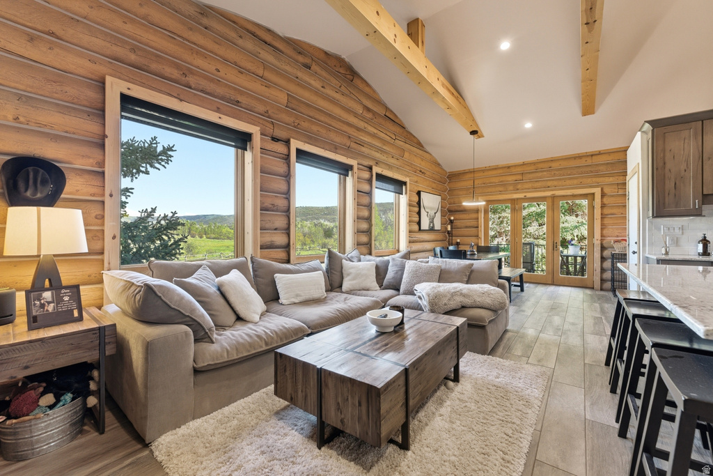 Expansive living area featuring natural wood log walls, vaulted ceilings with exposed beams, and large windows