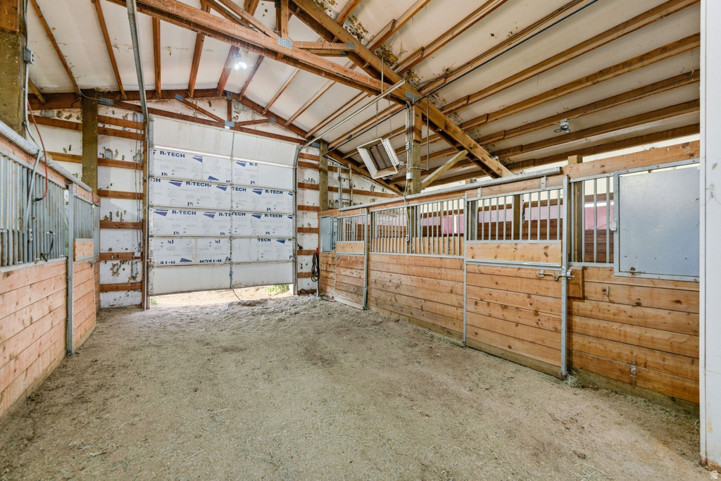 Spacious barn interior featuring exposed wood beam ceilings and a large roll-up door
