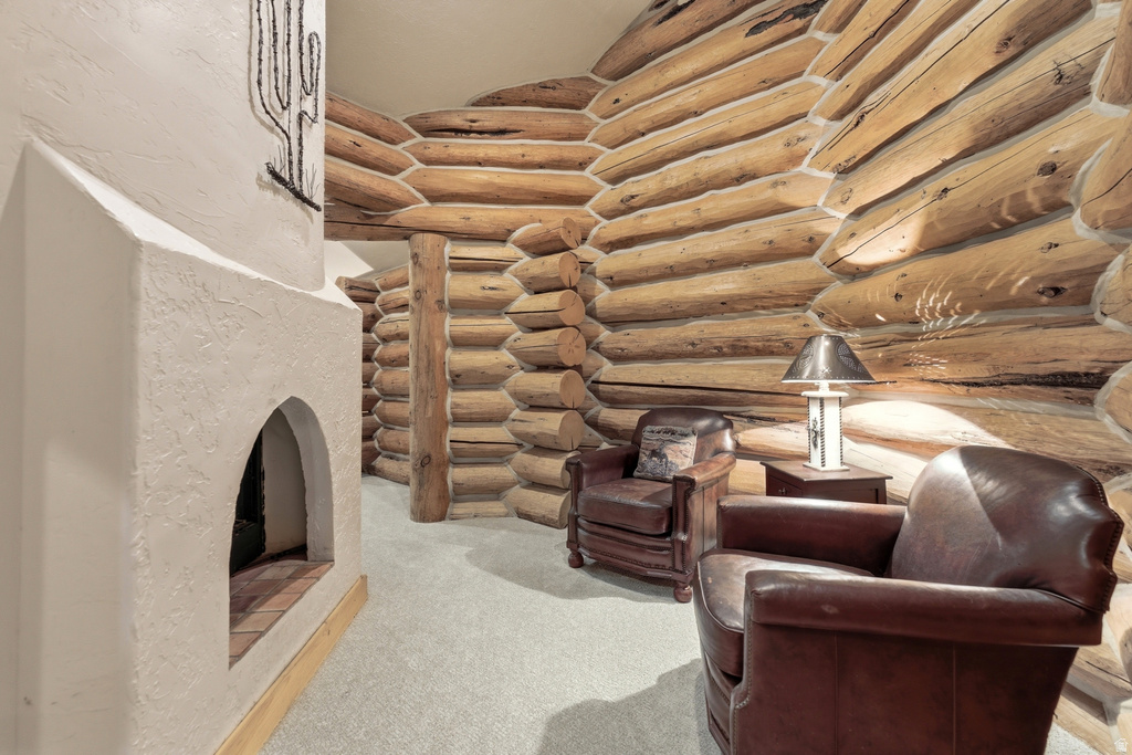 Rough-hewn log walls define this interior space, featuring a built-in fireplace with a stucco finish