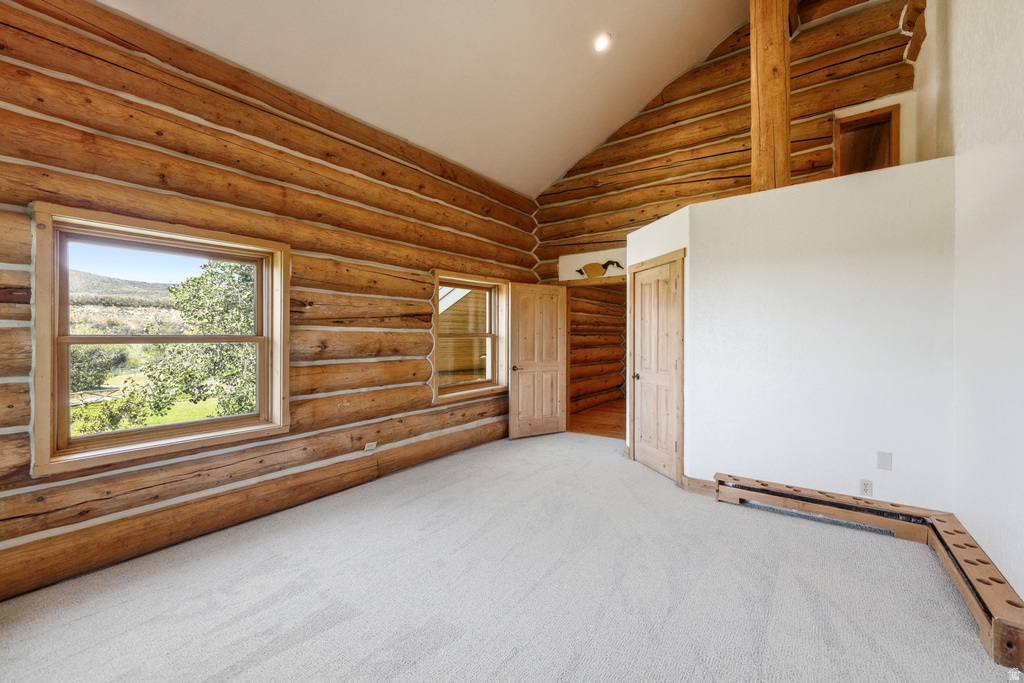 Expansive log cabin interior featuring a vaulted ceiling and light-toned carpet flooring