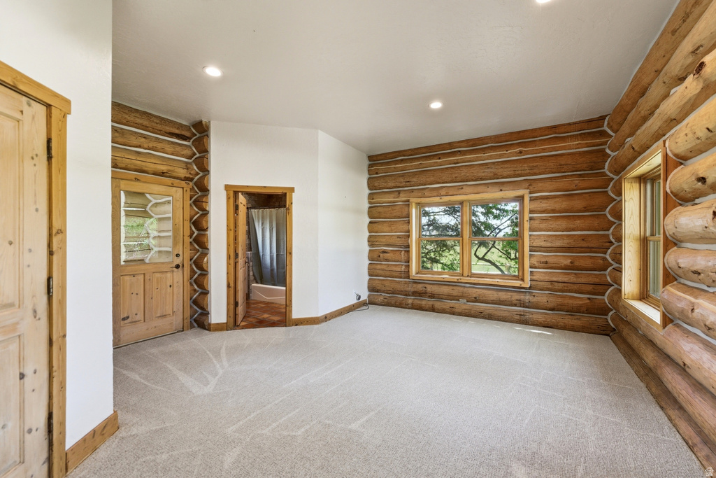 Expansive room featuring log walls and light-toned carpet flooring