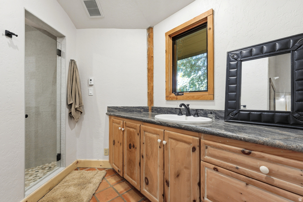 Bathroom featuring a wood-finish vanity with a single basin sink and dark countertop