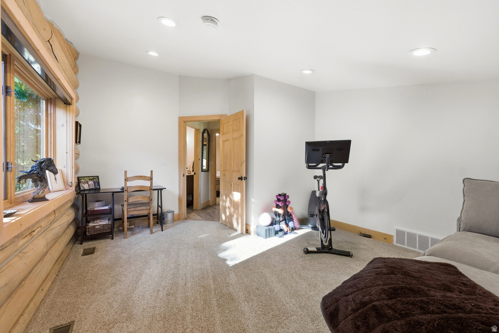 Spacious room featuring log wall construction, a large picture window, recessed lighting, and light-toned carpeting