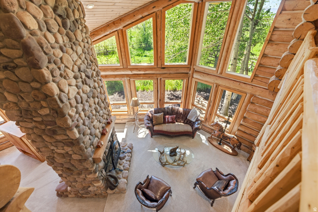 Great room featuring a floor-to-ceiling river rock fireplace with a wood mantle, complemented by extensive natural log construction
