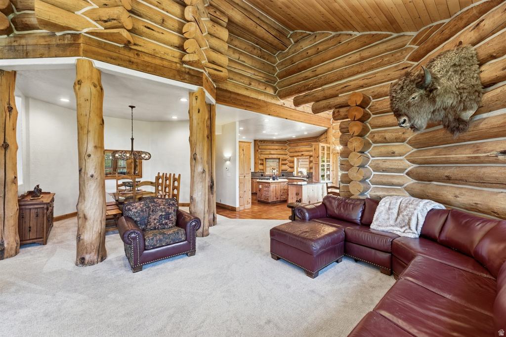 Spacious living area featuring log walls, exposed wood ceiling, and light-toned carpeting