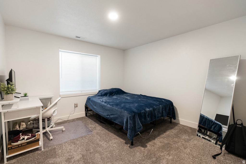 Carpeted room featuring a white-trimmed window with blinds, white walls, and an overhead light fixture
