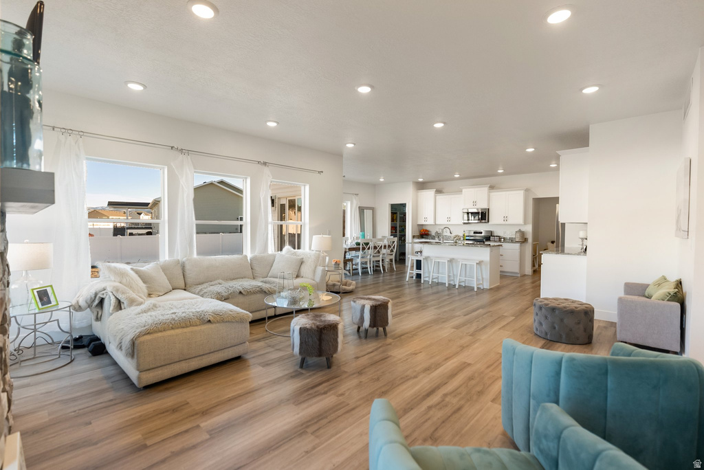 Spacious open-concept living area featuring wood-finish flooring, recessed lighting, and large windows