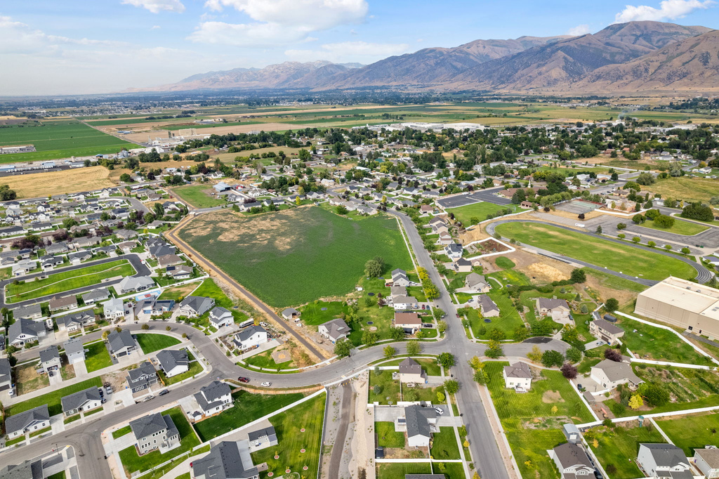 Expansive aerial perspective showcasing a residential development with surrounding green spaces and distant mountain ranges