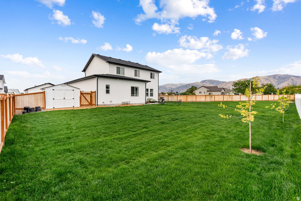 Expansive backyard featuring a lush green lawn, full wood privacy fencing, a white storage shed, and newly planted saplings