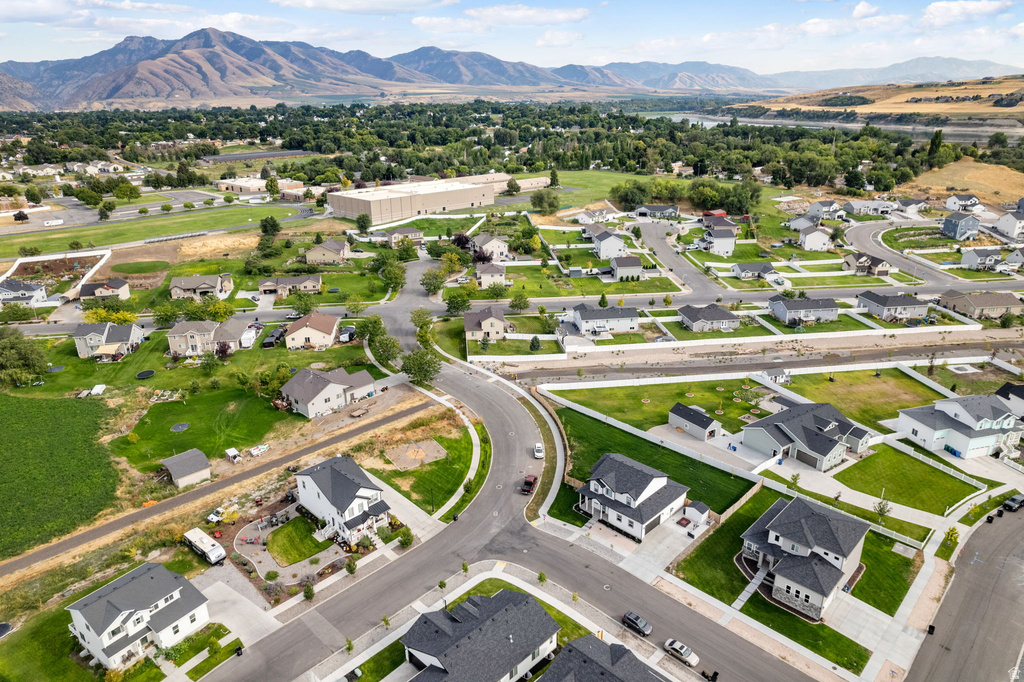 Aerial perspective showcasing a residential community with contemporary homes, mountain backdrop, paved streets, and green spaces