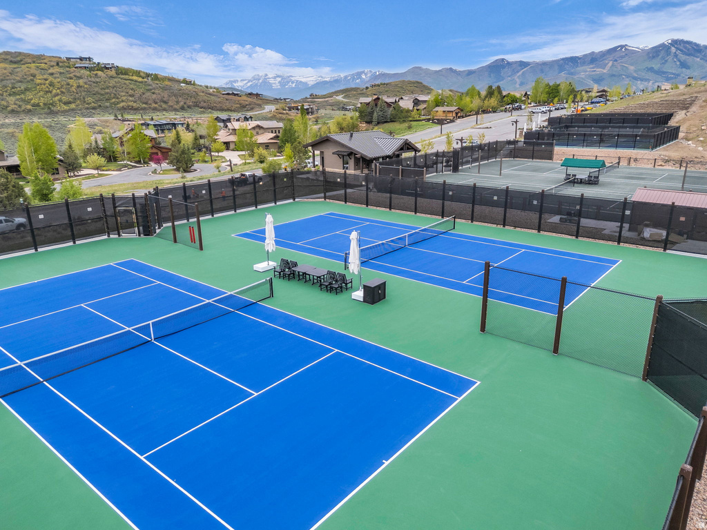 Tennis court complex featuring blue and green hard courts, perimeter fencing, and seating areas