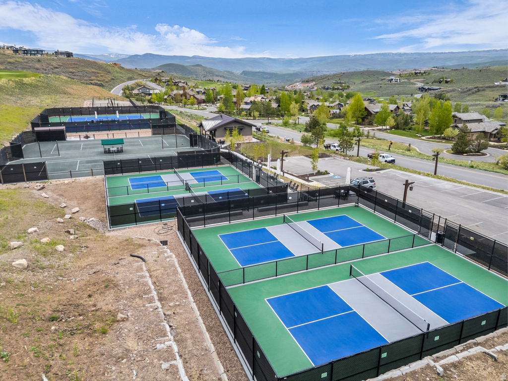 Multiple outdoor sports courts, including several pickleball courts with blue and gray surfaces, and tennis courts with green surfaces