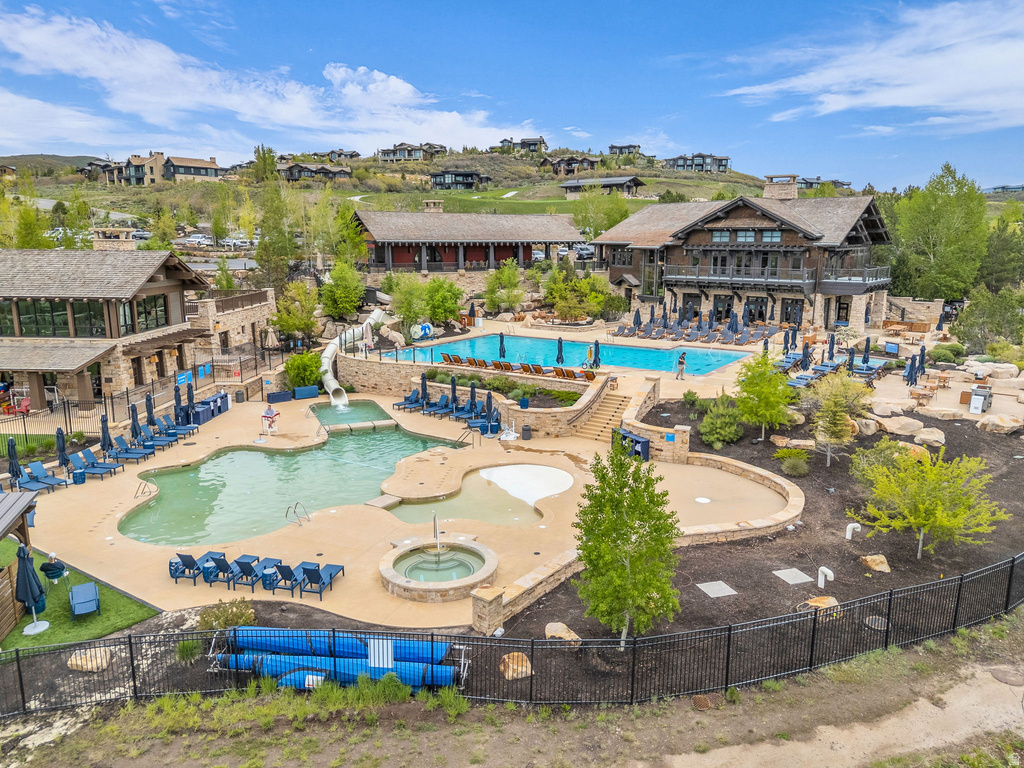 Resort-style pool area featuring multiple swimming pools, a spa, and a water slide, surrounded by stone-clad buildings with expansive outdoor decking