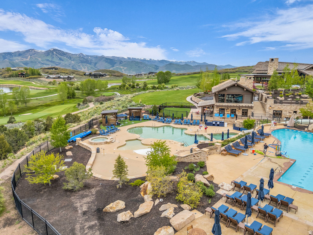 Expansive outdoor aquatic area featuring multiple pools, a hot tub, and an adjacent clubhouse with stone and wood siding