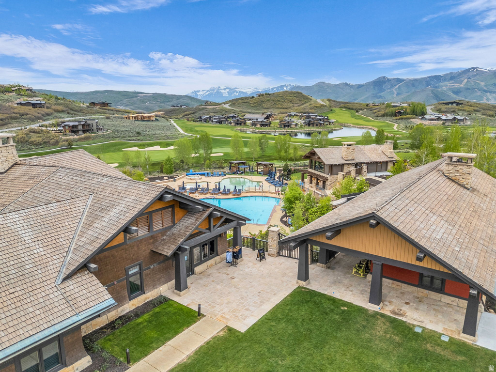 Expansive outdoor pool area with surrounding lounge seating, framed by gabled buildings with stone chimneys and wood siding